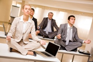 Portrait of meditating partners sitting on desks with their legs crossed in office; Shutterstock ID 39158518; PO: The Huffington Post; Job: The Huffington Post; Client: The Huffington Post; Other: The Huffington Post